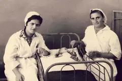 Dy infermiere pranë një shtrati, fotografi arkivi